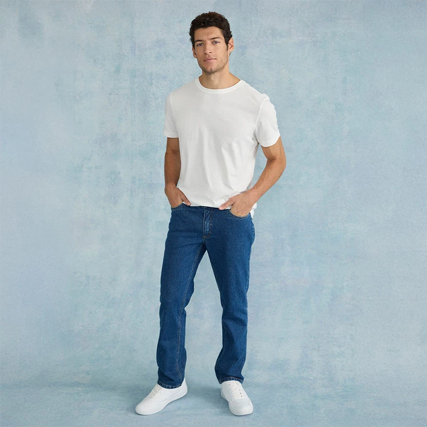 T-shirt blanc, jean bleu Regular Fit et sneakers blanches.