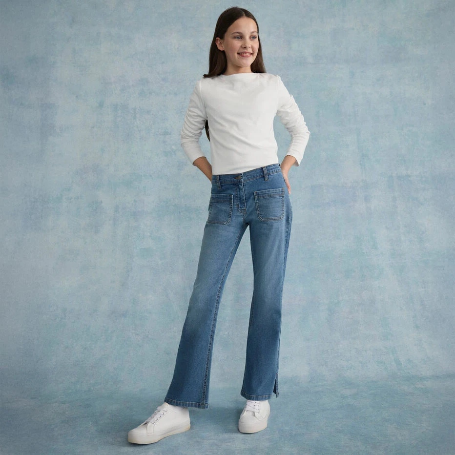 T‑shirt blanc à manches longues et au style épuré, associé à un jean décontracté et des baskets blanches.
