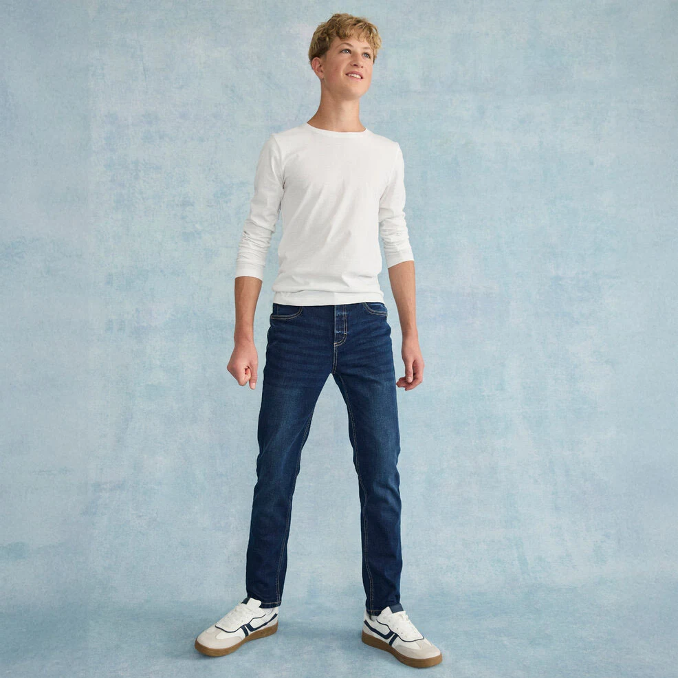 Look décontracté avec un t‑shirt blanc à manches longues, un jean classique et des baskets blanches.