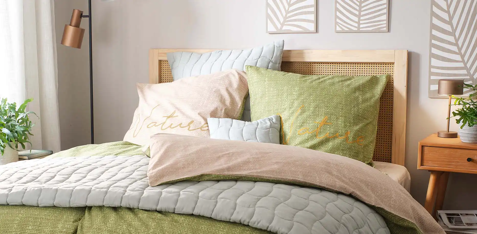 Parure de lit dans des tons vert et gris avec divers coussins créant une ambiance cosy dans la chambre à coucher.