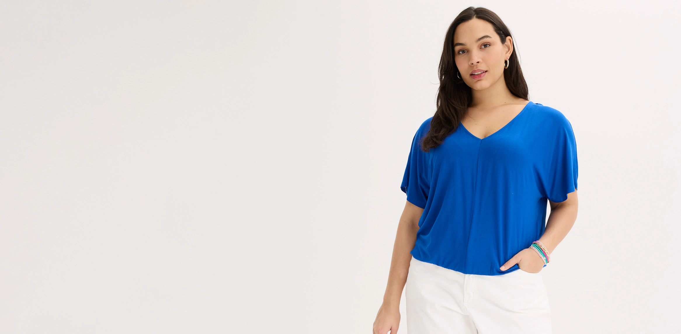 Look féminin avec un t-shirt oversize bleu à col V et un pantalon blanc.