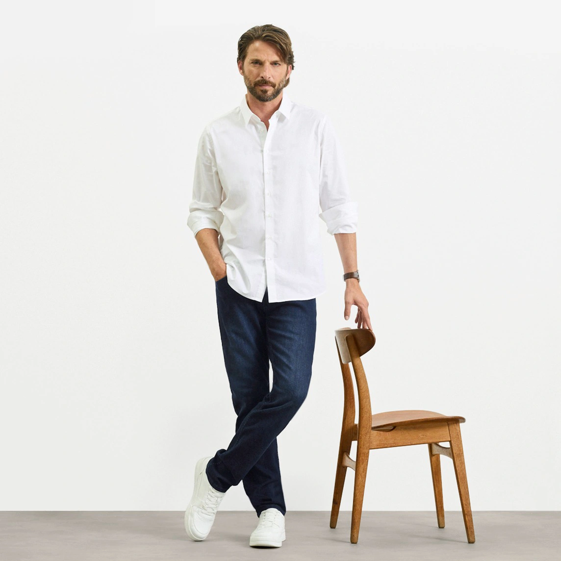 Chemise blanche, jean foncé coupe Slim Fit et baskets blanches.