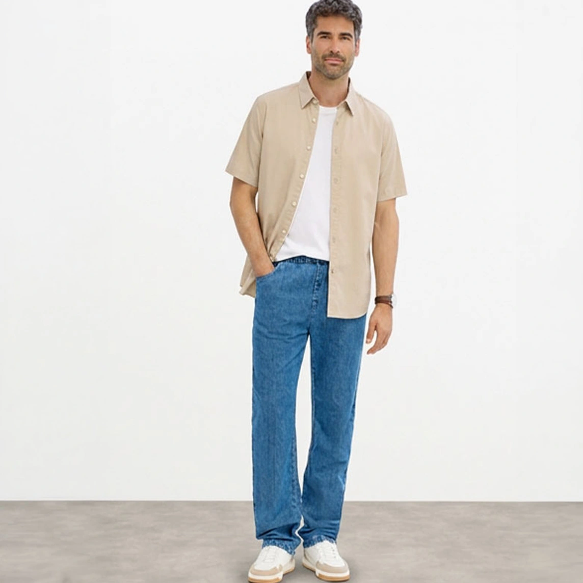 Chemise beige à manches courtes, T-shirt blanc, jean bleu coupe Classic Fit et baskets blanches.