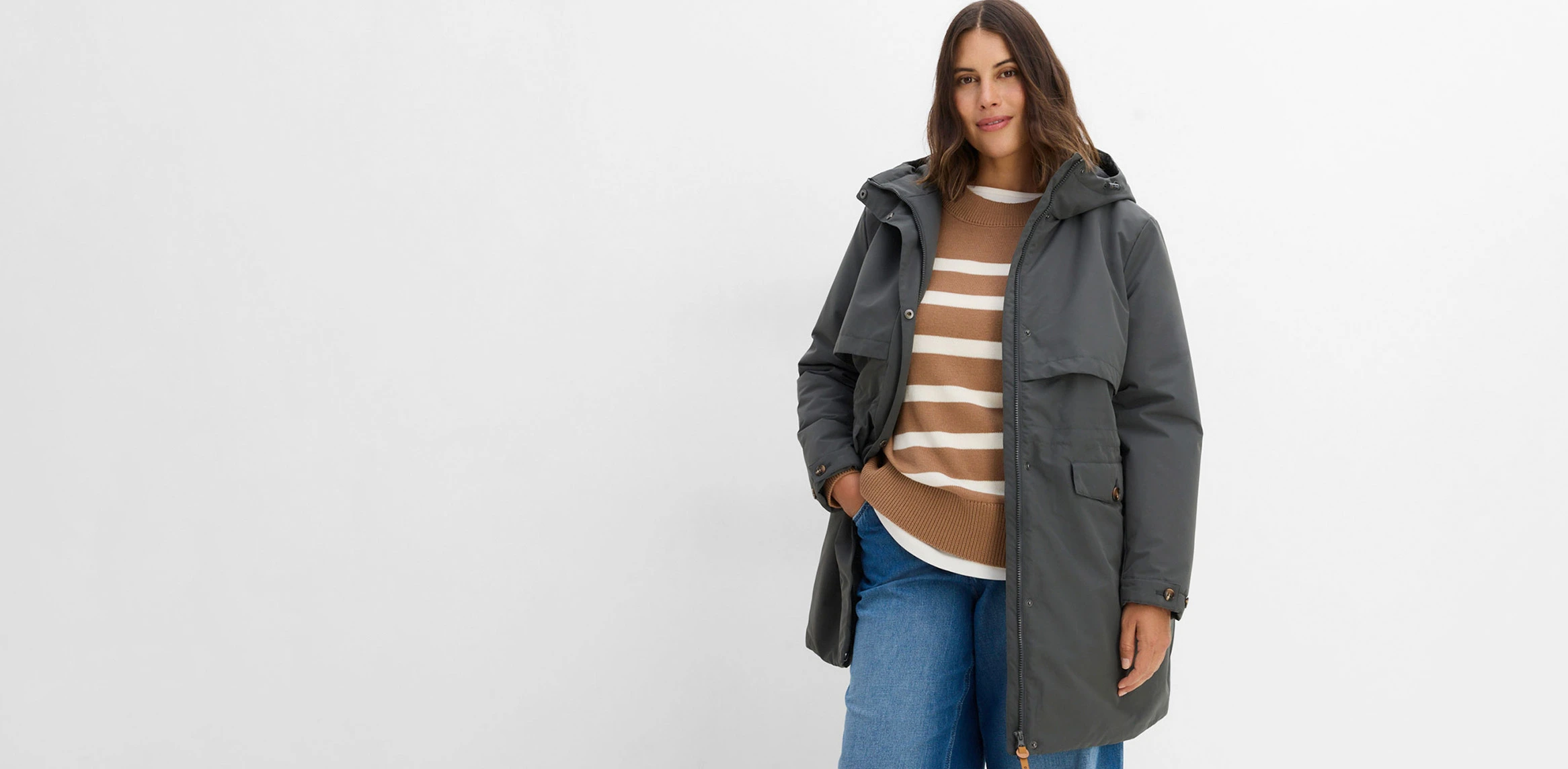 Veste technique grise, pull à rayures et jean confortable.