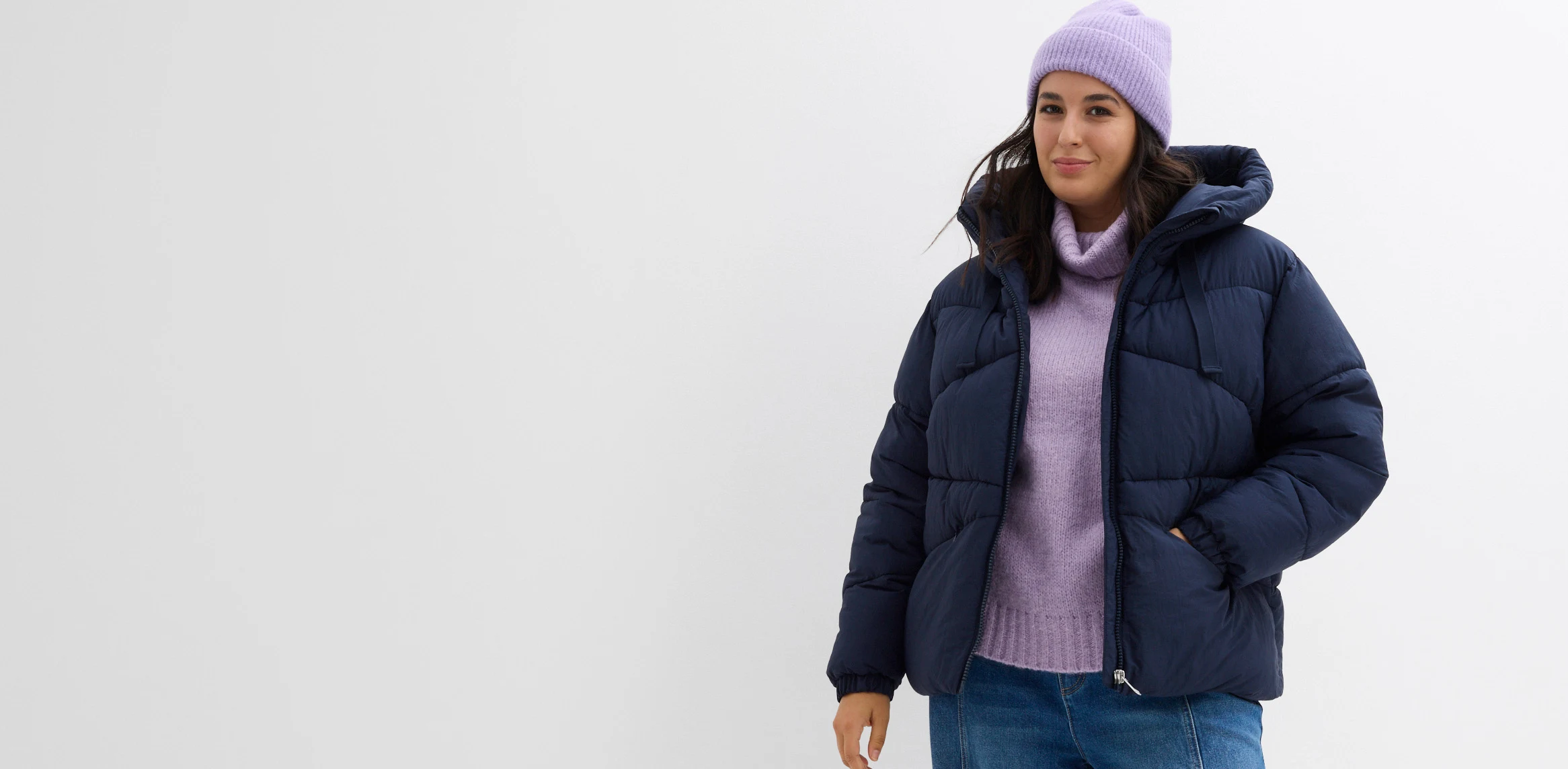 Doudoune bleu marine, pull à col roulé et bonnet lilas.