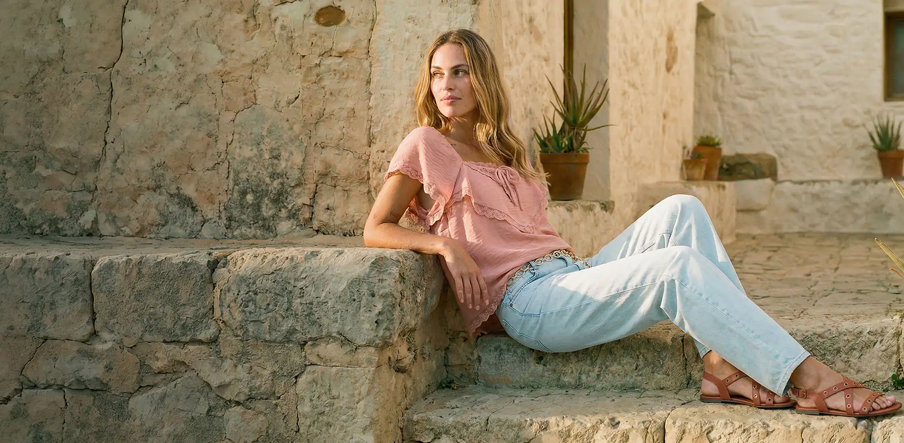 Blouse rose tendre à volants et jean bleu clair.