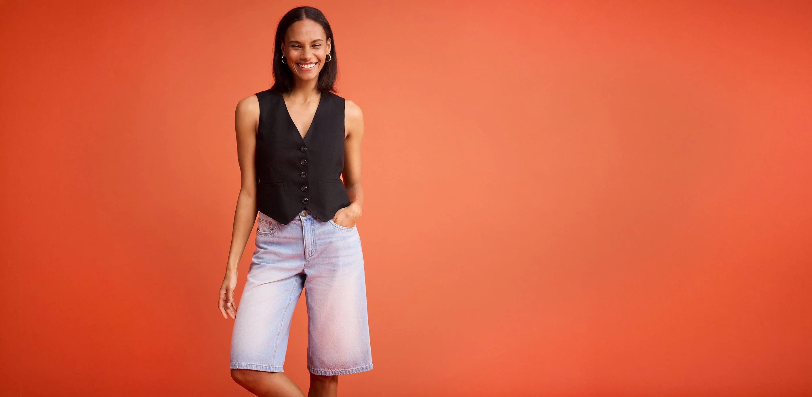 Gilet noir sans manches à boutons associé à un short en jean bleu clair.