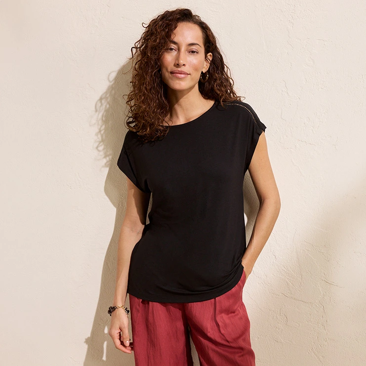 Une femme vêtue d'un haut noir à manches courtes et d'un pantalon rouge.