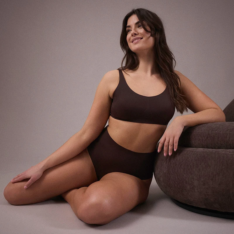 Une femme vêtue d'un soutien-gorge marron sans couture avec un slip assorti.