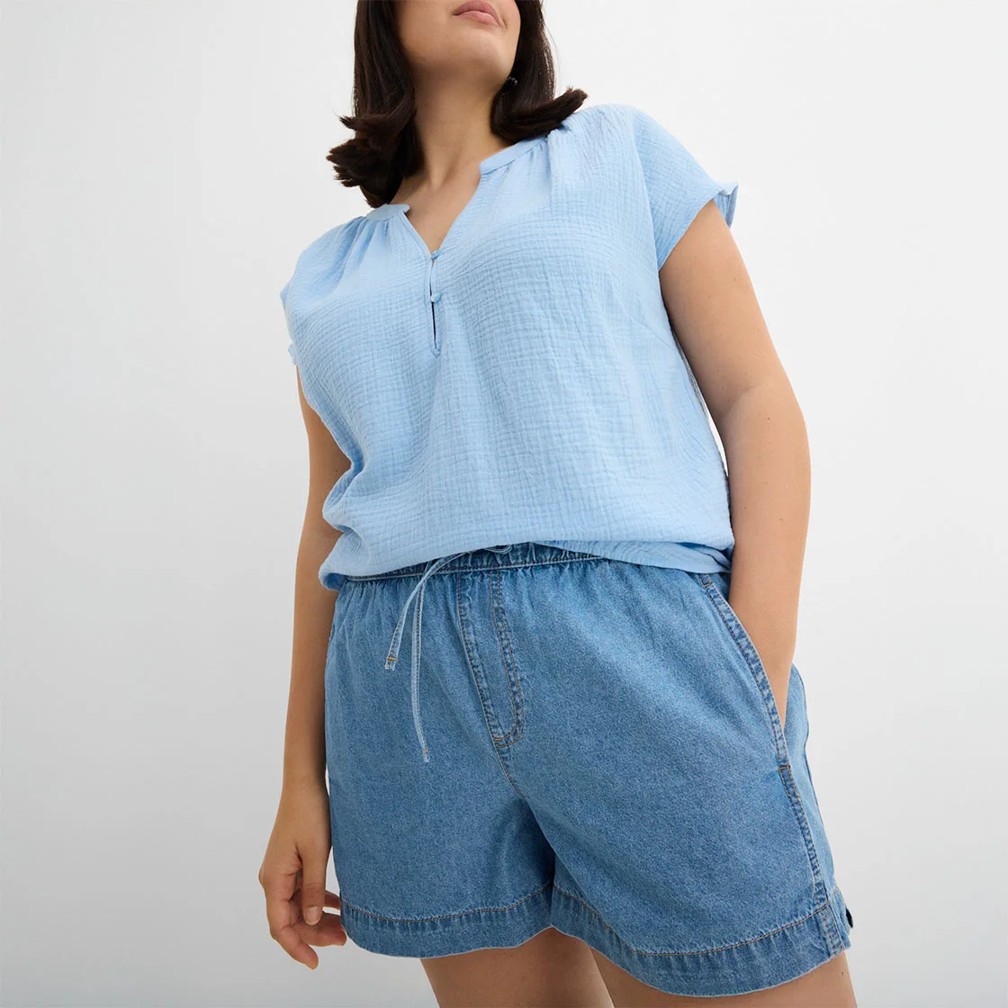Haut bleu clair sans manches et short en jean pour un look estival décontracté.
