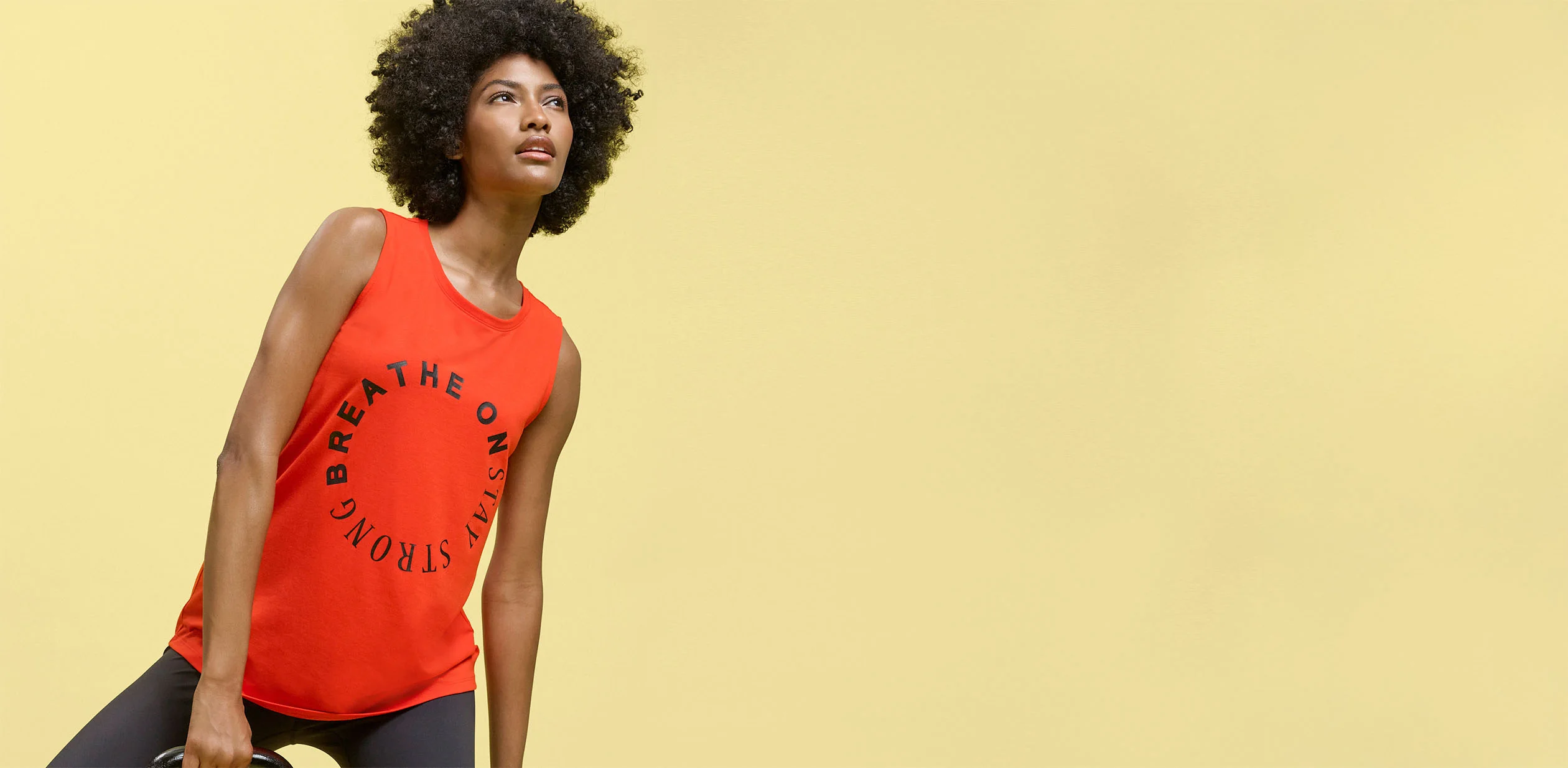 Débardeur rouge avec inscription "Breathe On Stay Strong" et legging foncé pour le sport.