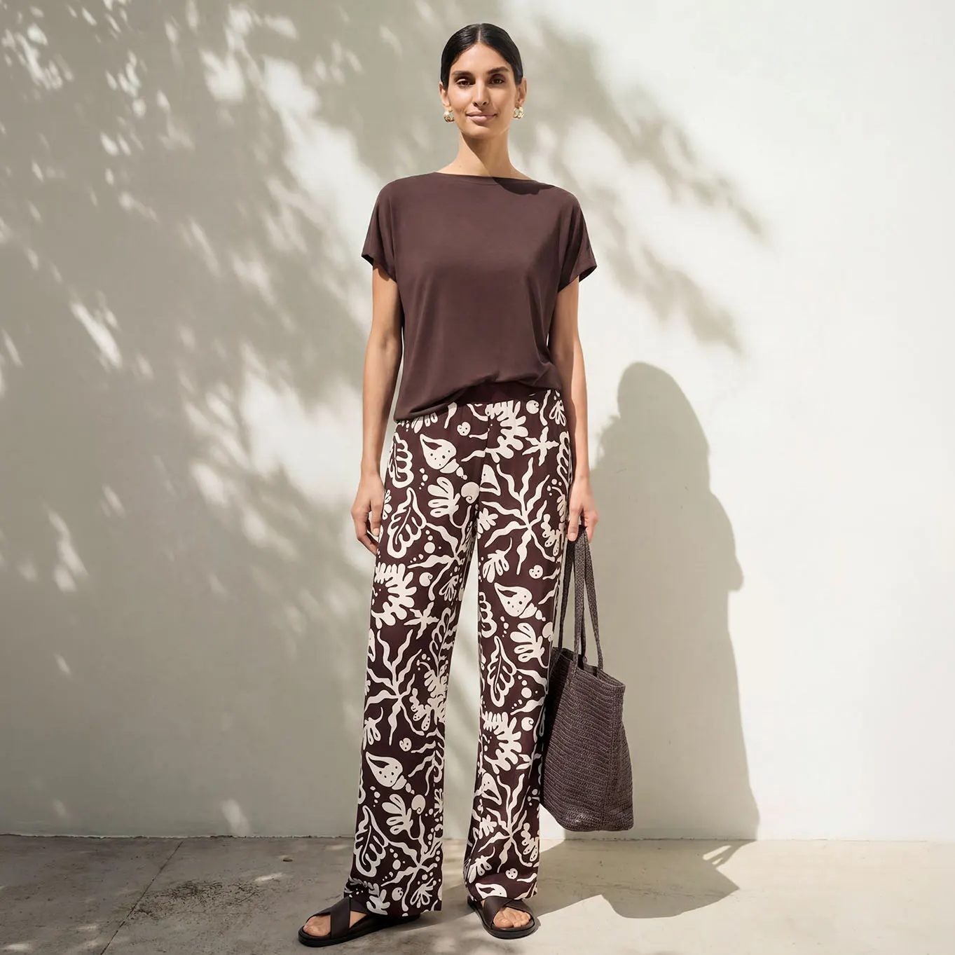 Haut marron uni, pantalon large imprimé, complété d'une paire de sandales noires et d'un sac.