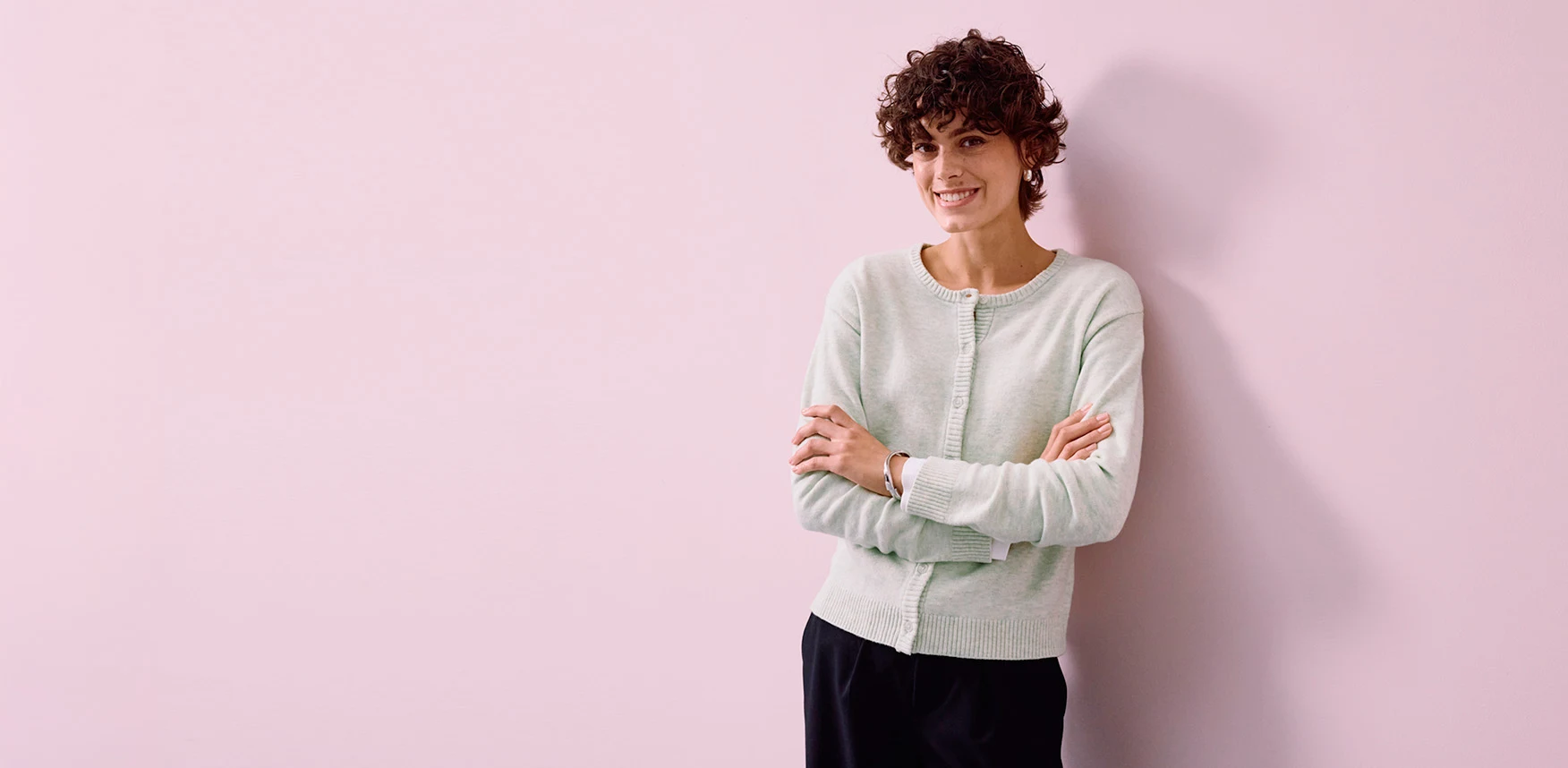 Cardigan vert clair associé à un pantalon noir élégant.