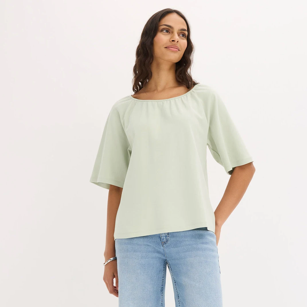 Blouse vert clair élégante à manches larges associée à un jean décontracté.