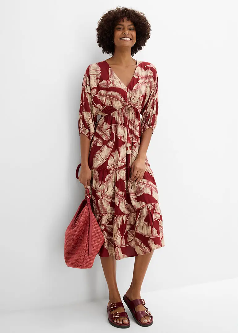 Robe midi aérienne à motif végétal, sac et sandales rouges assortis.