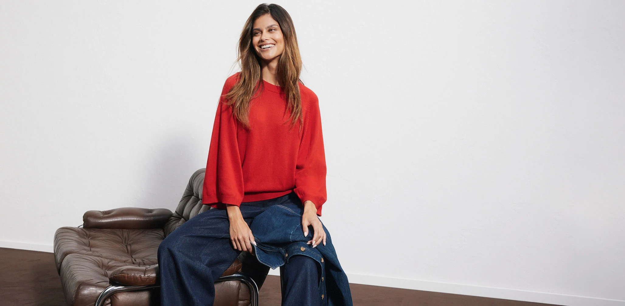 Pull rouge, jean large et veste en jean assortie.