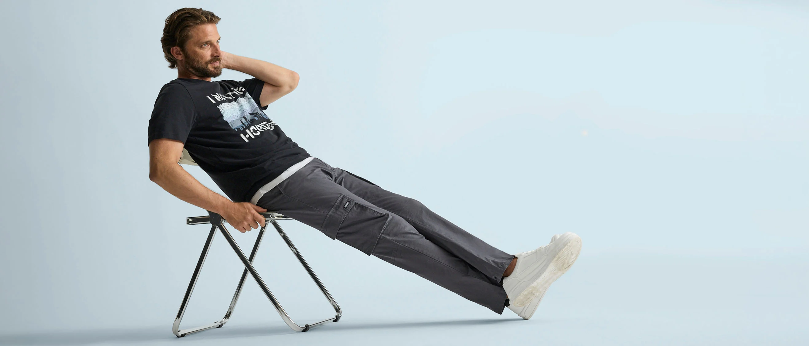 T-shirt noir à imprimé, pantalon cargo gris confortable et sneakers blanches décontractées.