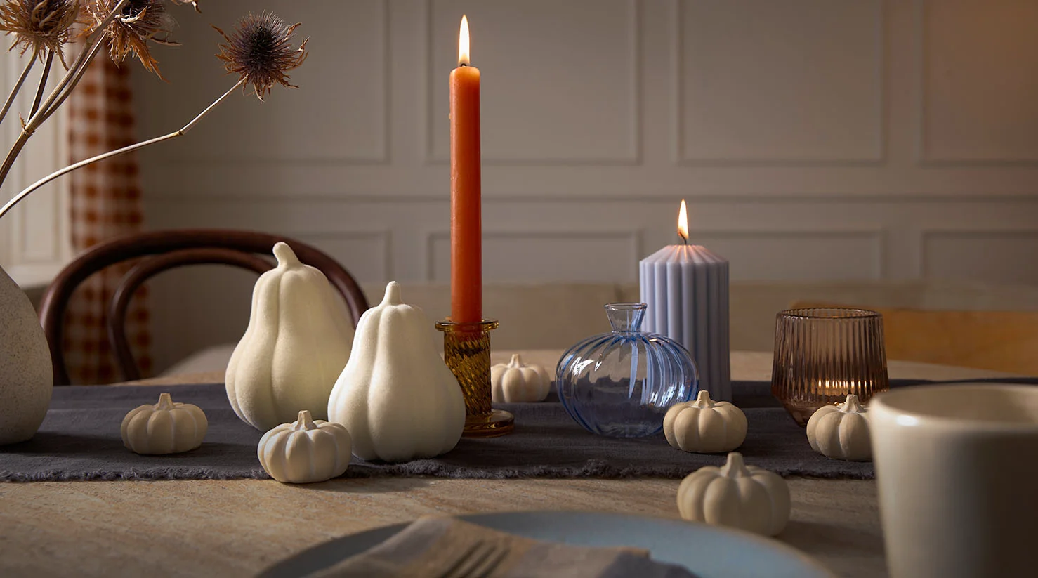 Décoration automnale avec des citrouilles blanches et une bougie.