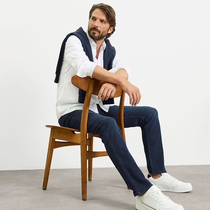 Look élégant et décontracté : chemise blanche, pull bleu, jean et baskets blanches.
