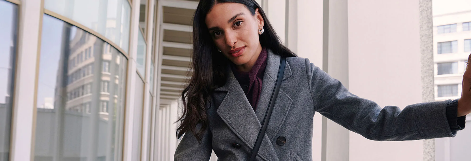Manteau court gris, pull à col roulé de couleur foncée et pantalon rouge bordeaux.