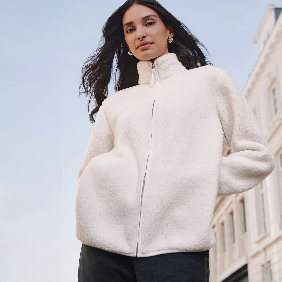 Veste douillette en polaire peluche de couleur crème avec fermeture zippée, pantalon de couleur foncée mode.