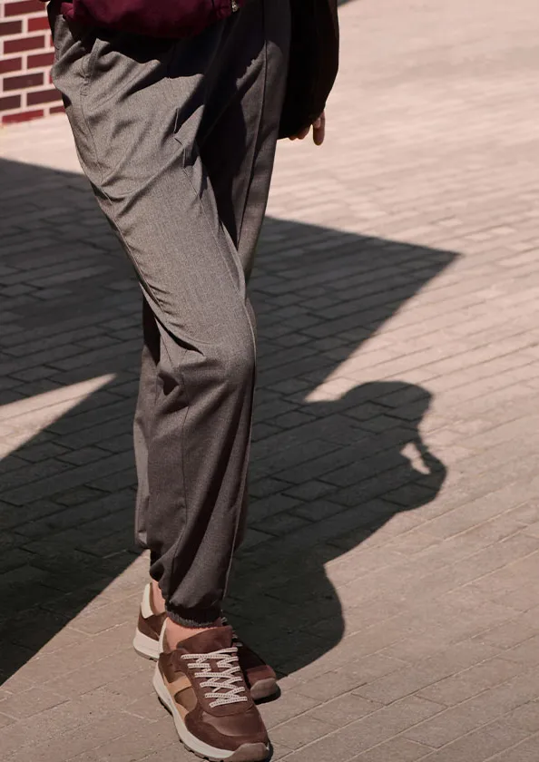 Pantalon en tissu gris et sneakers marron pour un look décontracté-chic.