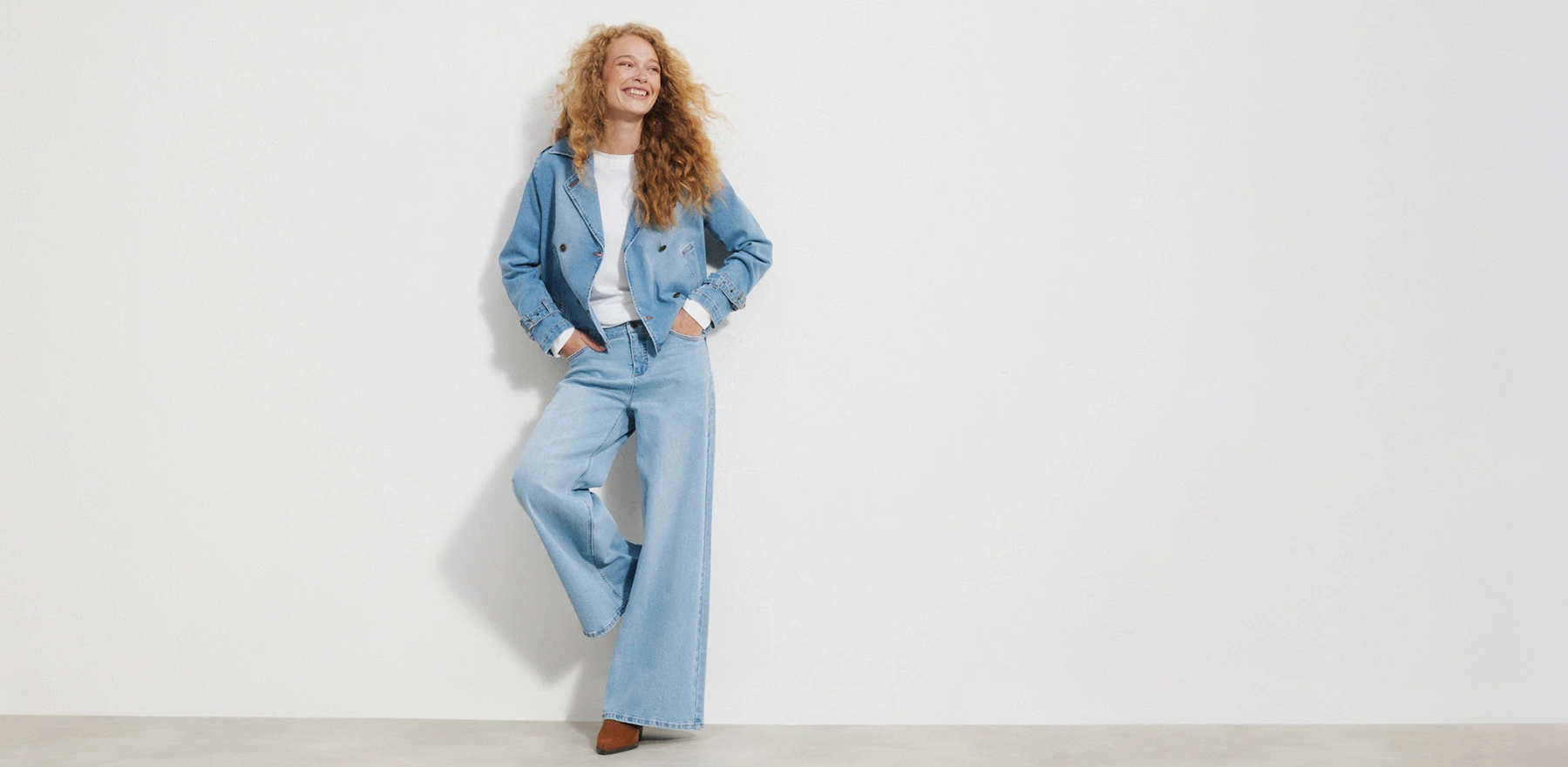 Veste courte en jean, pantalon large, T-shirt blanc et chaussures marron.