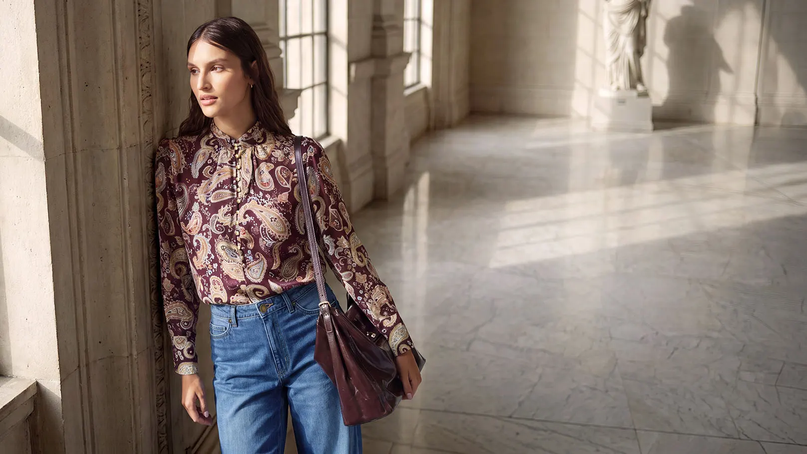 Look mode : chemisier à motif paisley, jean large, chaussures chic et sac à main assorti.