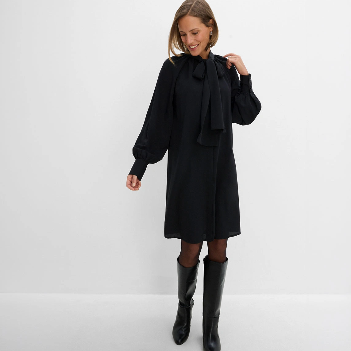 Une robe-chemise à col lavallière associée à une paire de bottes.