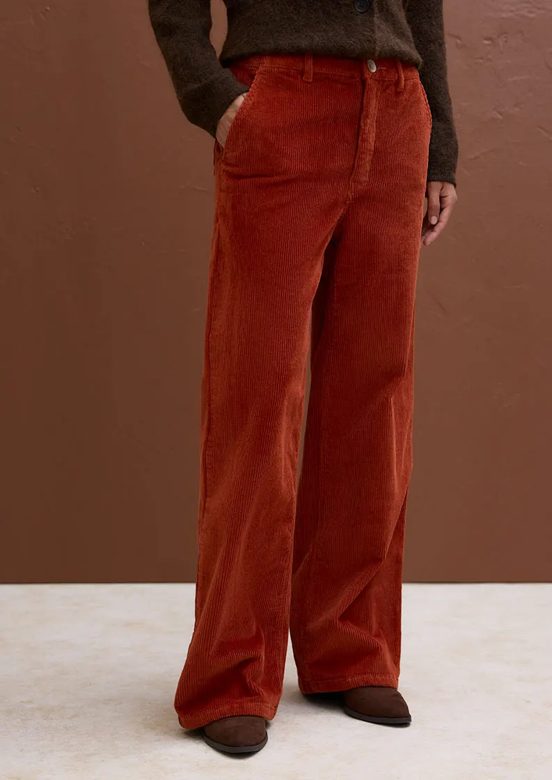 Femme vêtue d'un pantalon large en velours côtelé dans une teinte chaude.