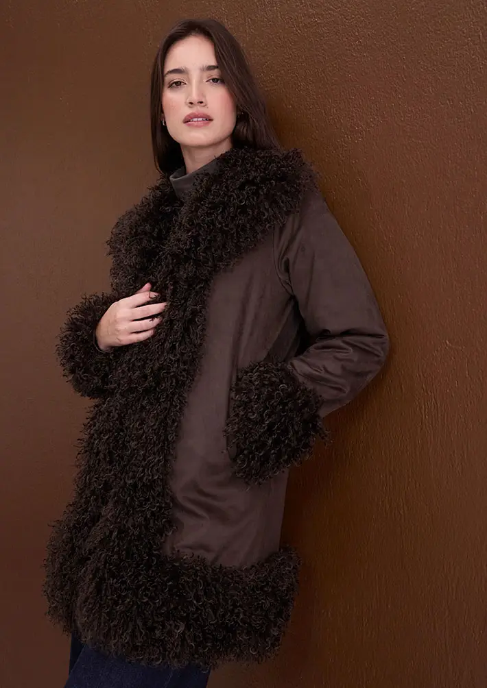 Manteau marron avec col et poignets douillets, un pull à col roulé en dessous.
