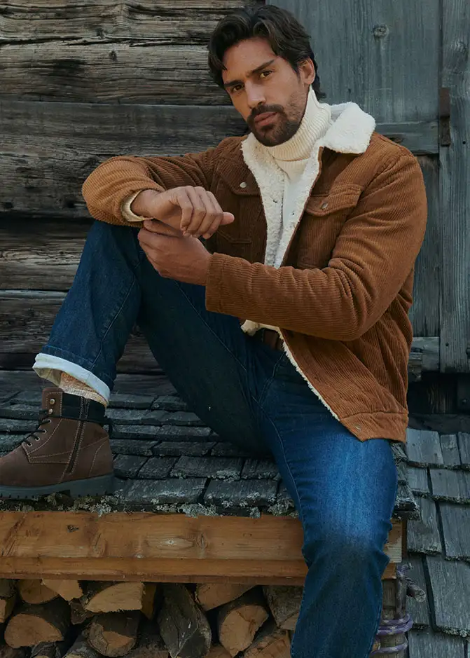 Veste en velours côtelé marron, pull blanc à col roulé, jean et boots doublées.